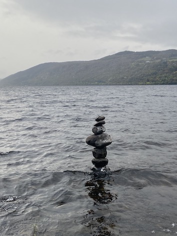 Several rocks stacked on top of each other in the lake, also called a Scottish Cairn.